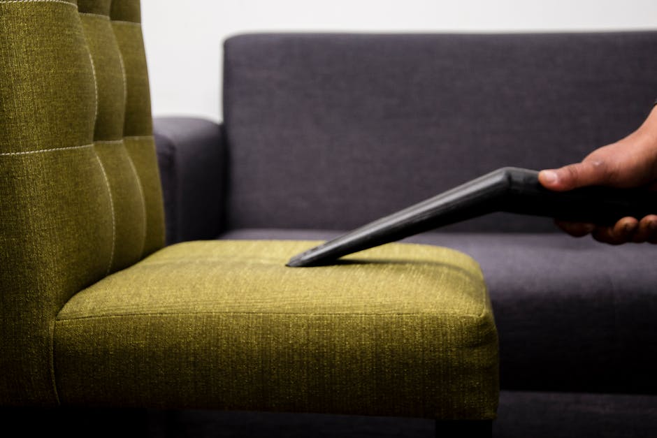 A white upholstered vintage sofa with tufted fabric and rolled arms is positioned against a white decorative wall panel in a well-lit room. The sofa's surface appears clean and smooth, with no visible